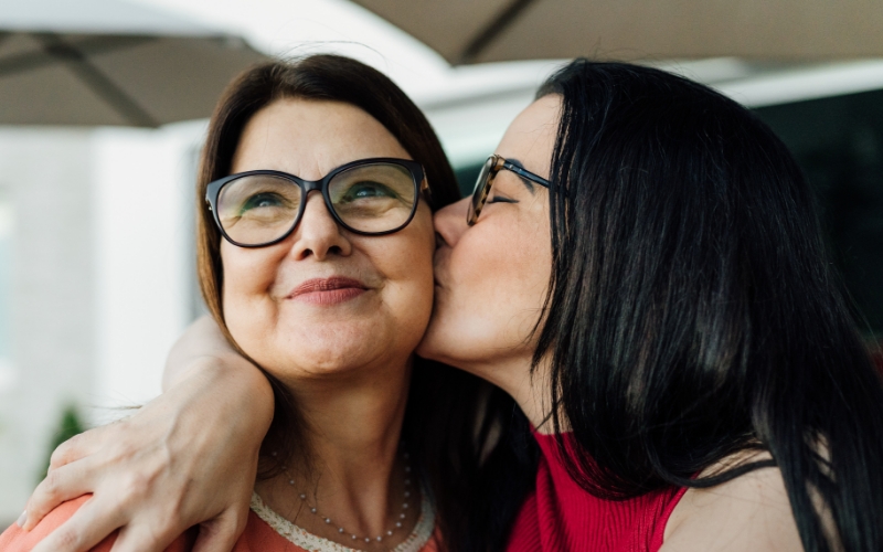 Two women wearing glasses embracing