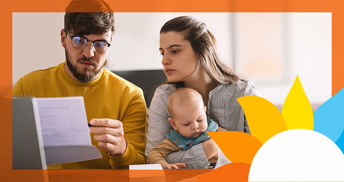concerned couple with baby looking at a bill